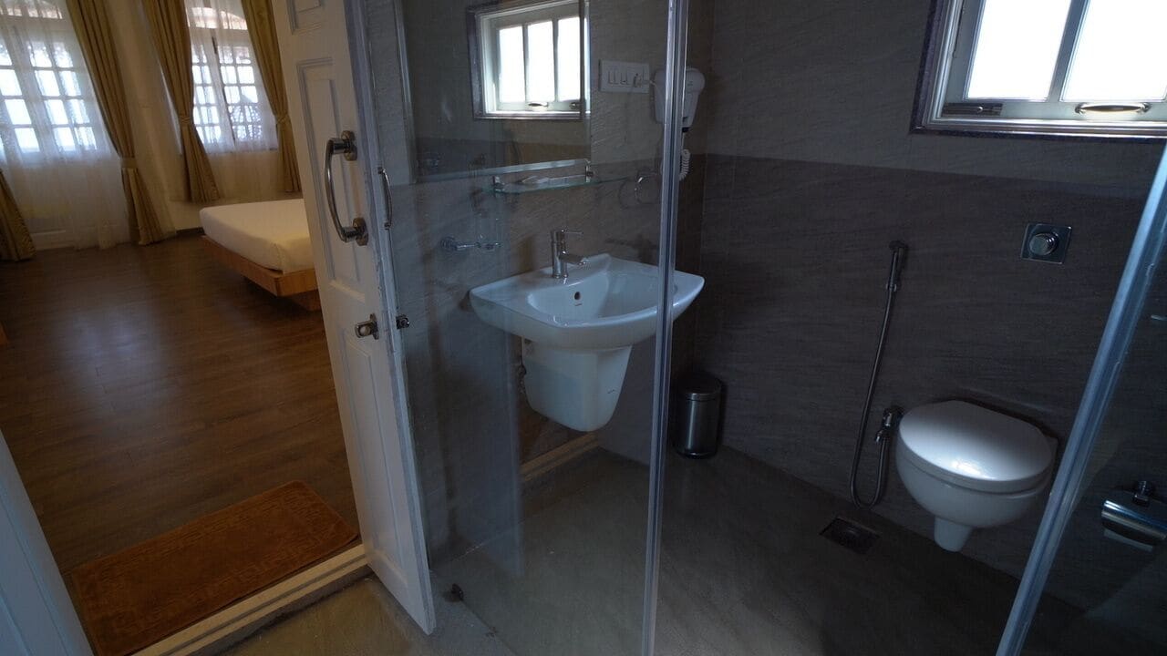 A bathroom with a glass shower enclosure, a sink, and a toilet.