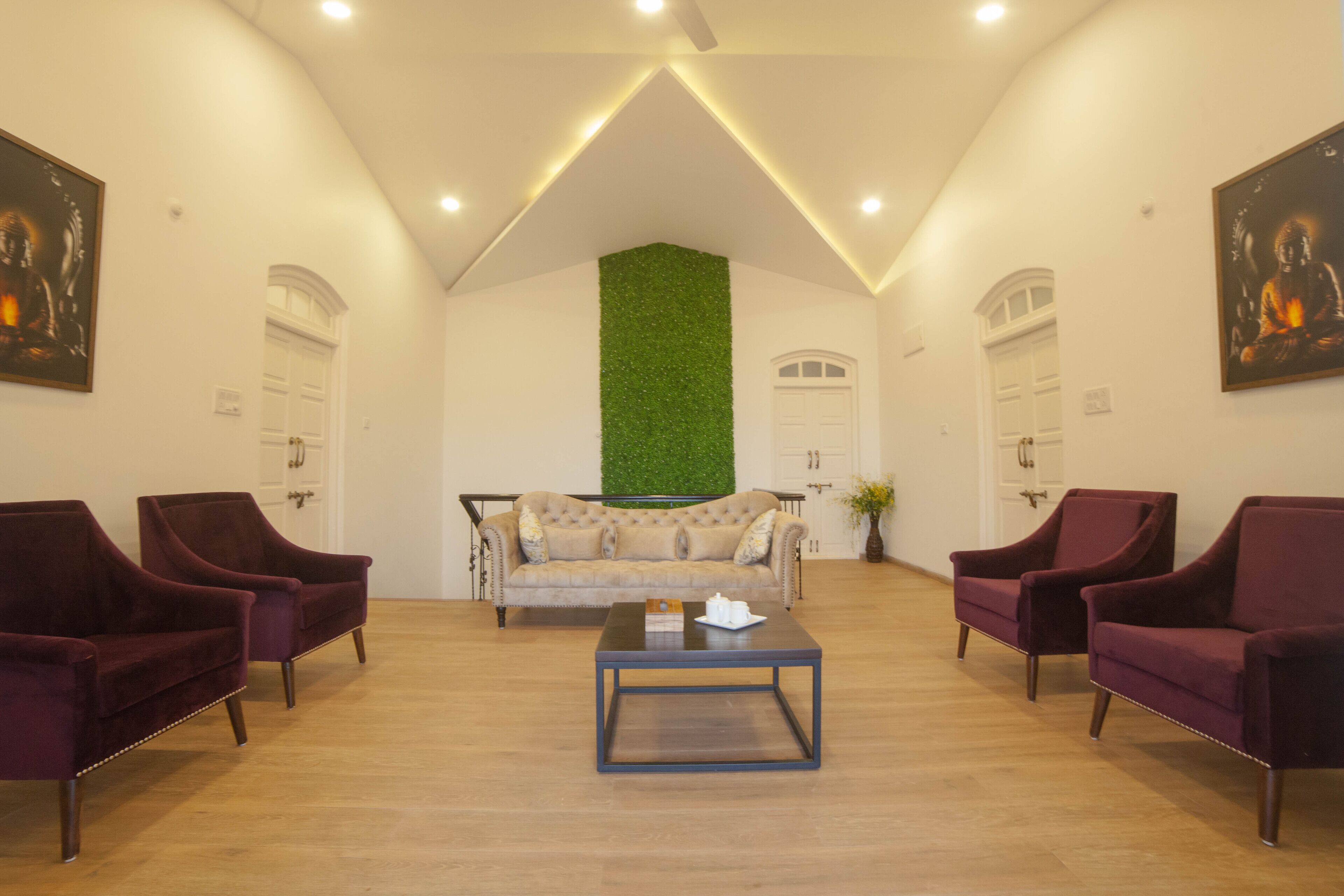 Un vestíbulo espacioso con techo alto, pared decorada en color verde, un sofá y dos sillones.