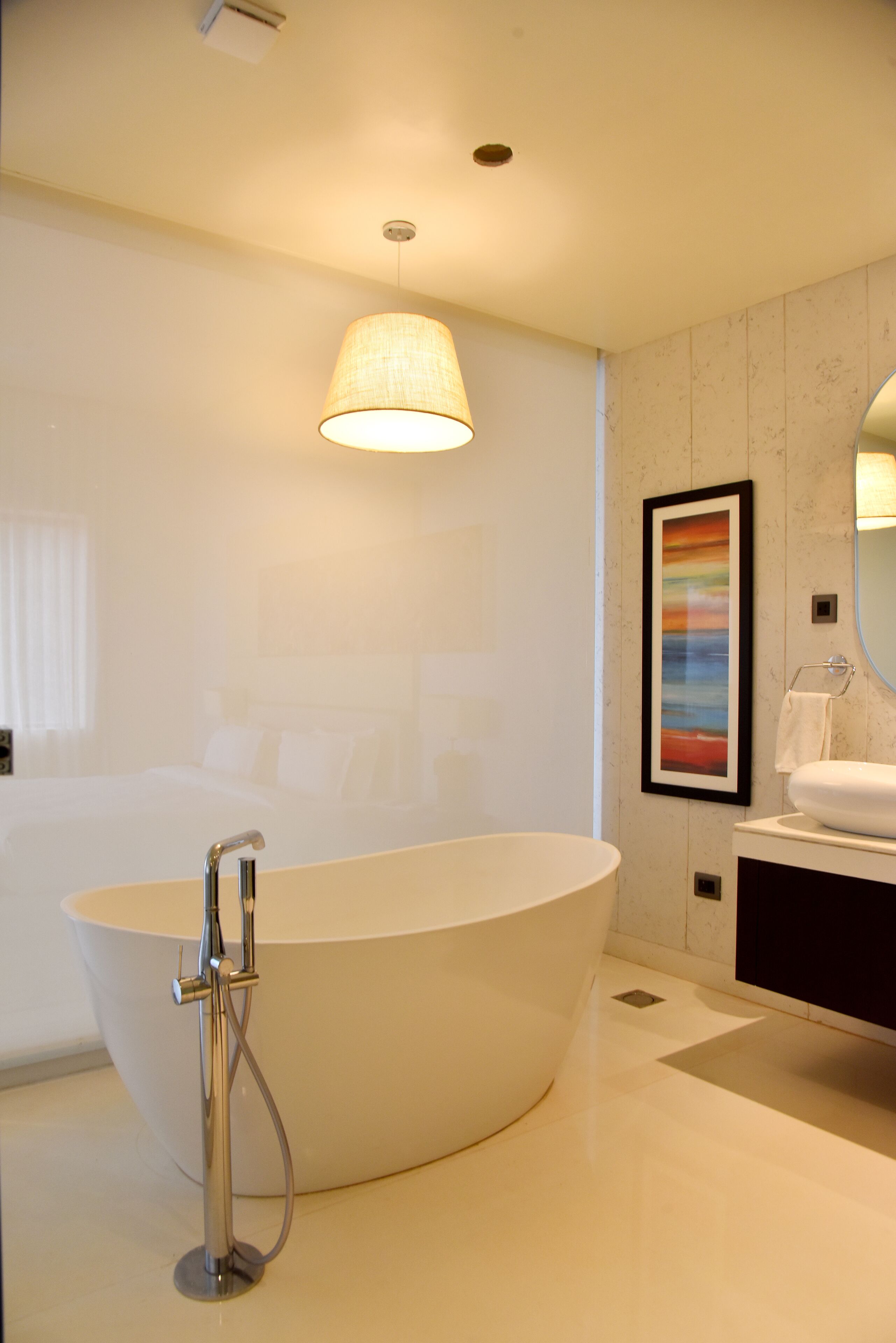 Une salle de bain moderne avec une baignoire sur pieds, un grand miroir et une œuvre d’art encadrée accrochée au mur.