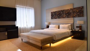 Une chambre moderne avec un grand lit, un téléviseur à écran plat, une table de chevet avec une lampe et un élément décoratif mural.