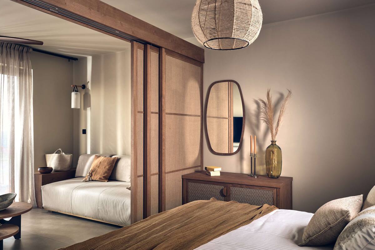 Un dormitorio moderno con cama, mesita de noche y un espejo grande.