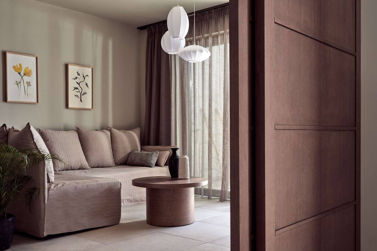 Un salón con un sofá color beige, una mesa de centro redonda y una planta en maceta.
