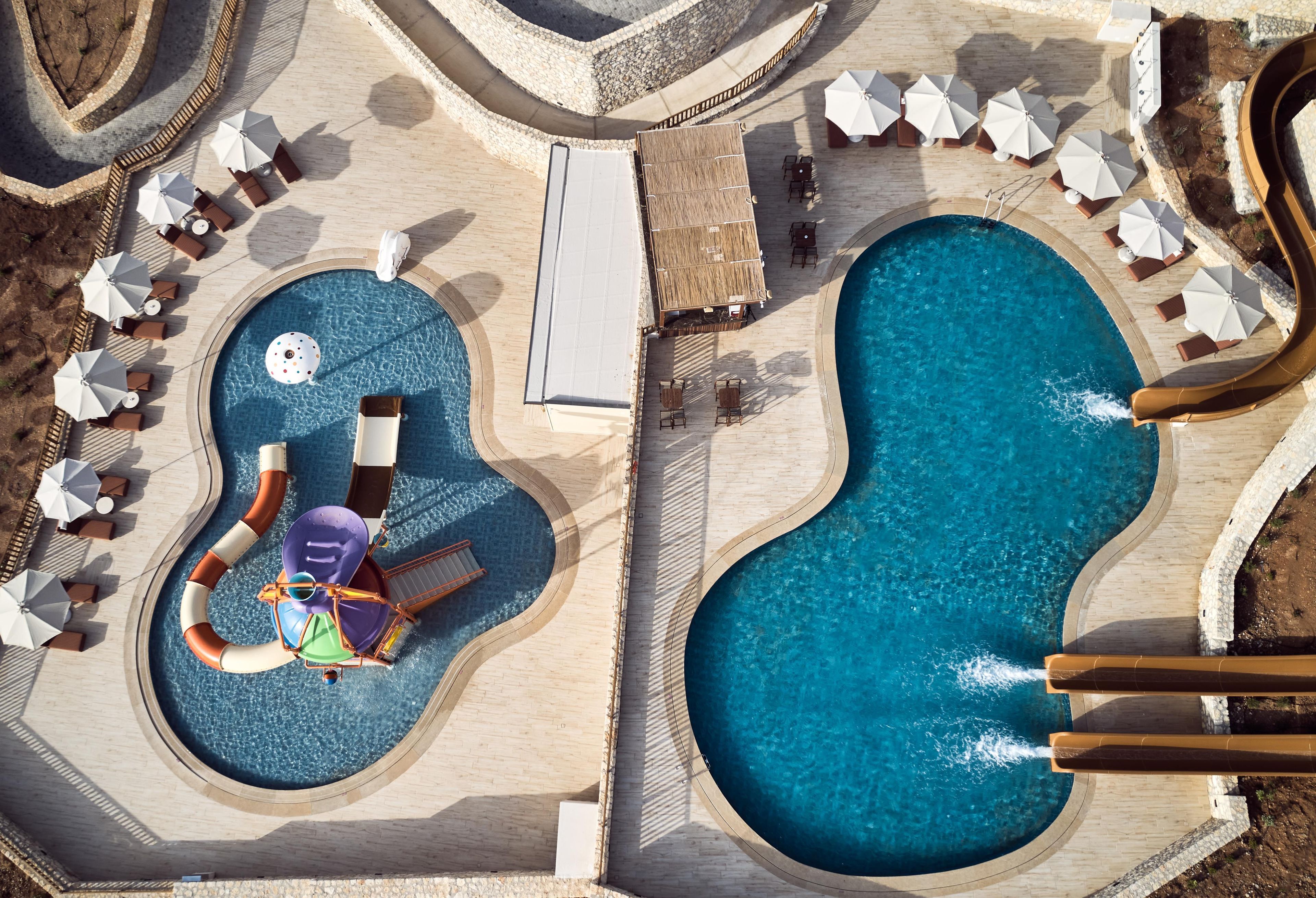 A large outdoor swimming pool with multiple lounge areas and umbrellas.