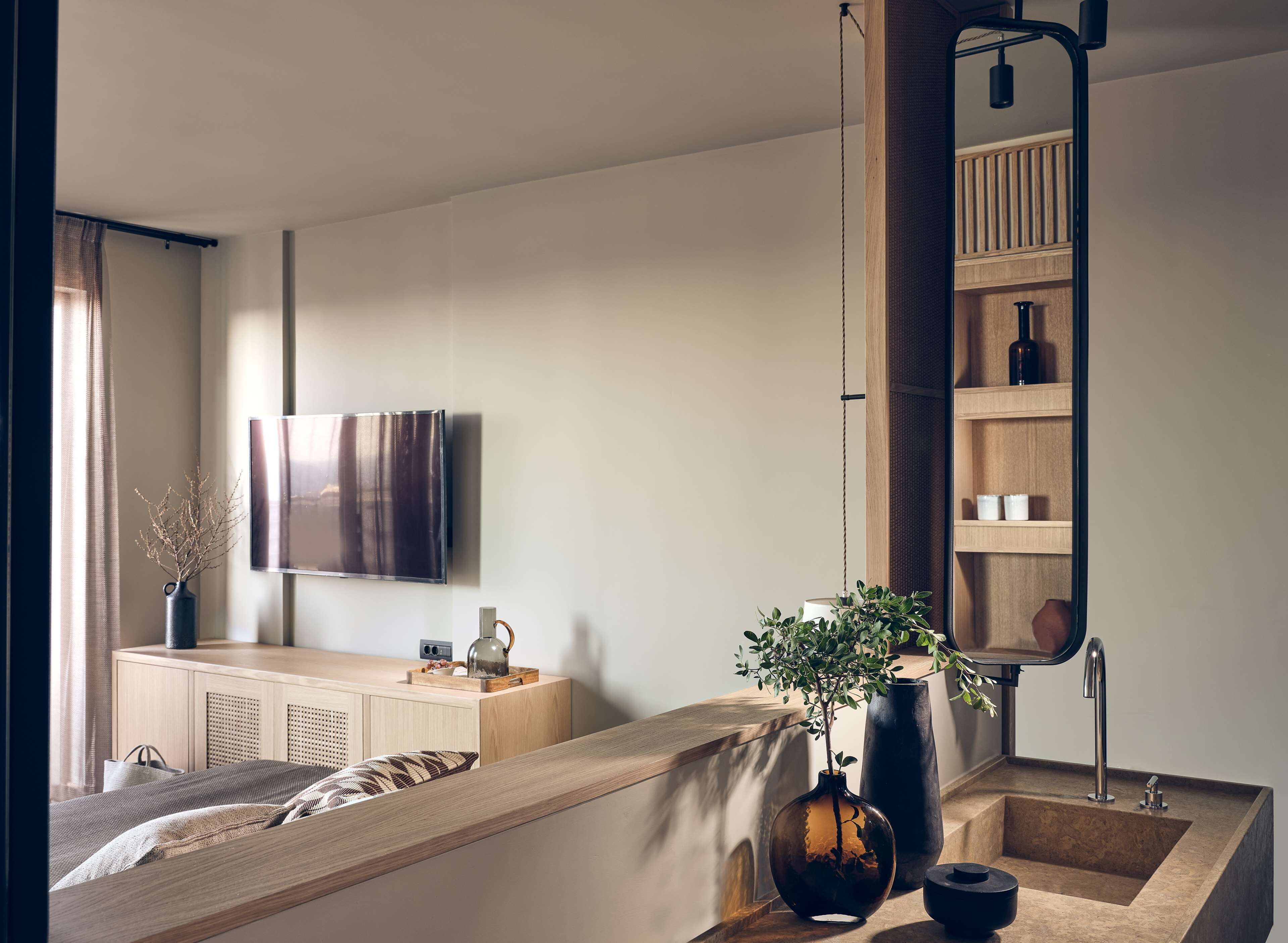 A modern bedroom with a bed, bedside table, and a large mirror.