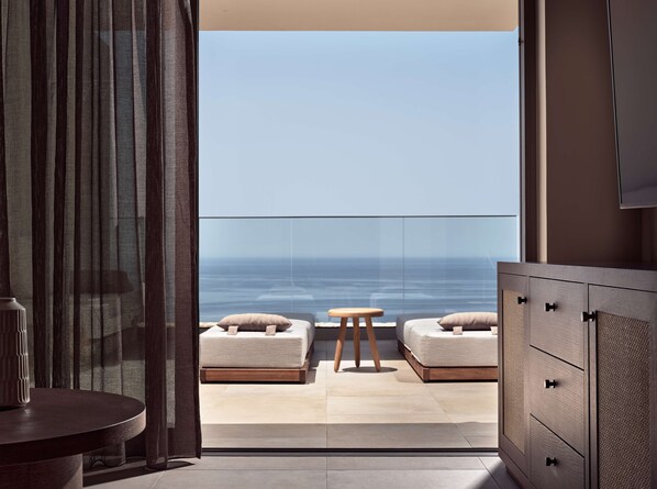 A balcony with a view of the ocean, a sofa, a small stool, and a cabinet. - The Royal Senses Resort & Spa Crete, Curio Collection Hilton (Mylopotamos)