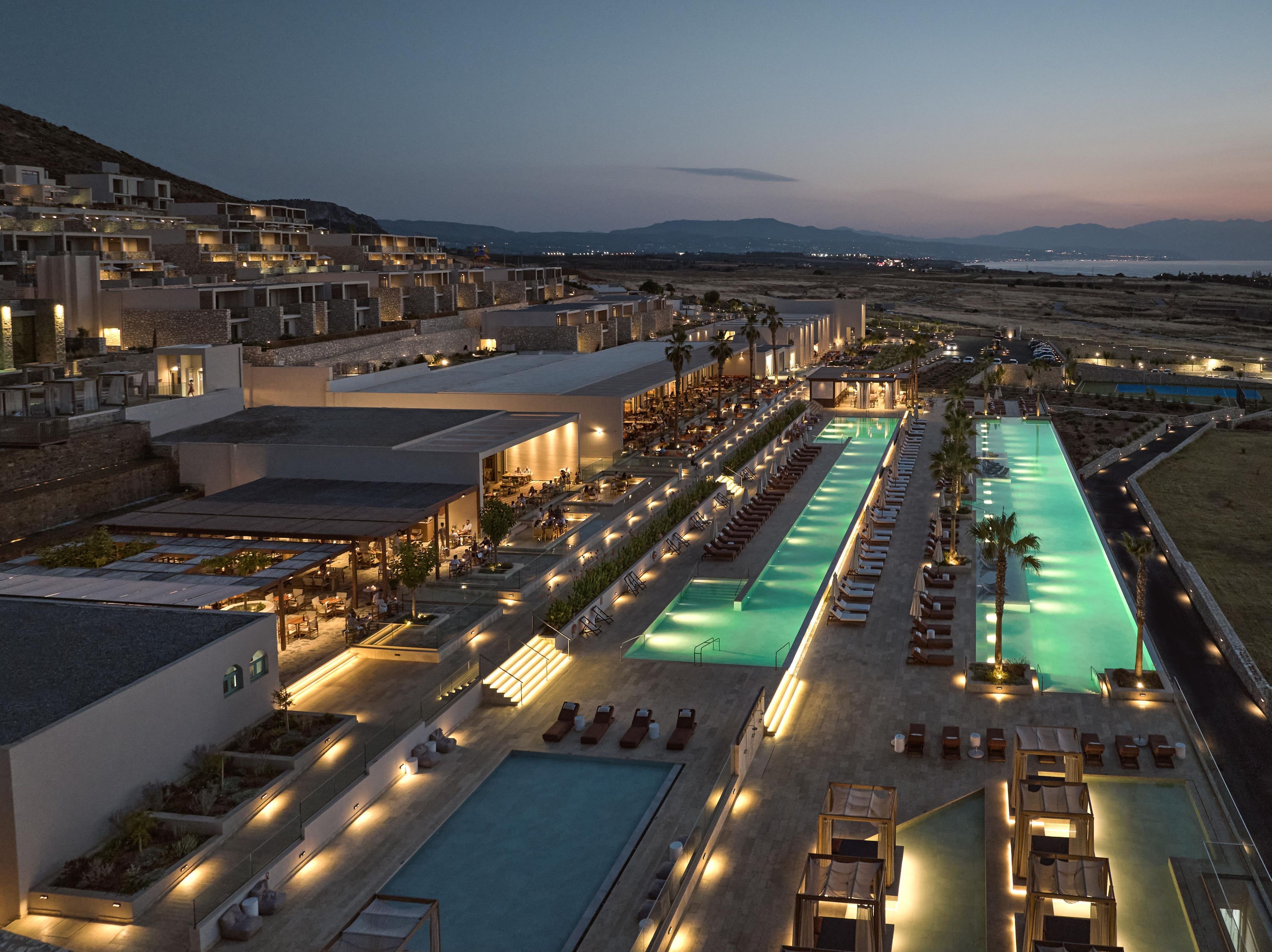 Een resort met meerdere zwembaden, buiten zitgedeeltes en uitzicht op verre bergen.