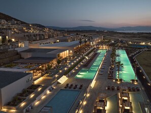 A resort with multiple swimming pools, outdoor seating areas, and a view of distant mountains. - The Royal Senses Resort & Spa Crete, Curio Collection Hilton (Mylopotamos)