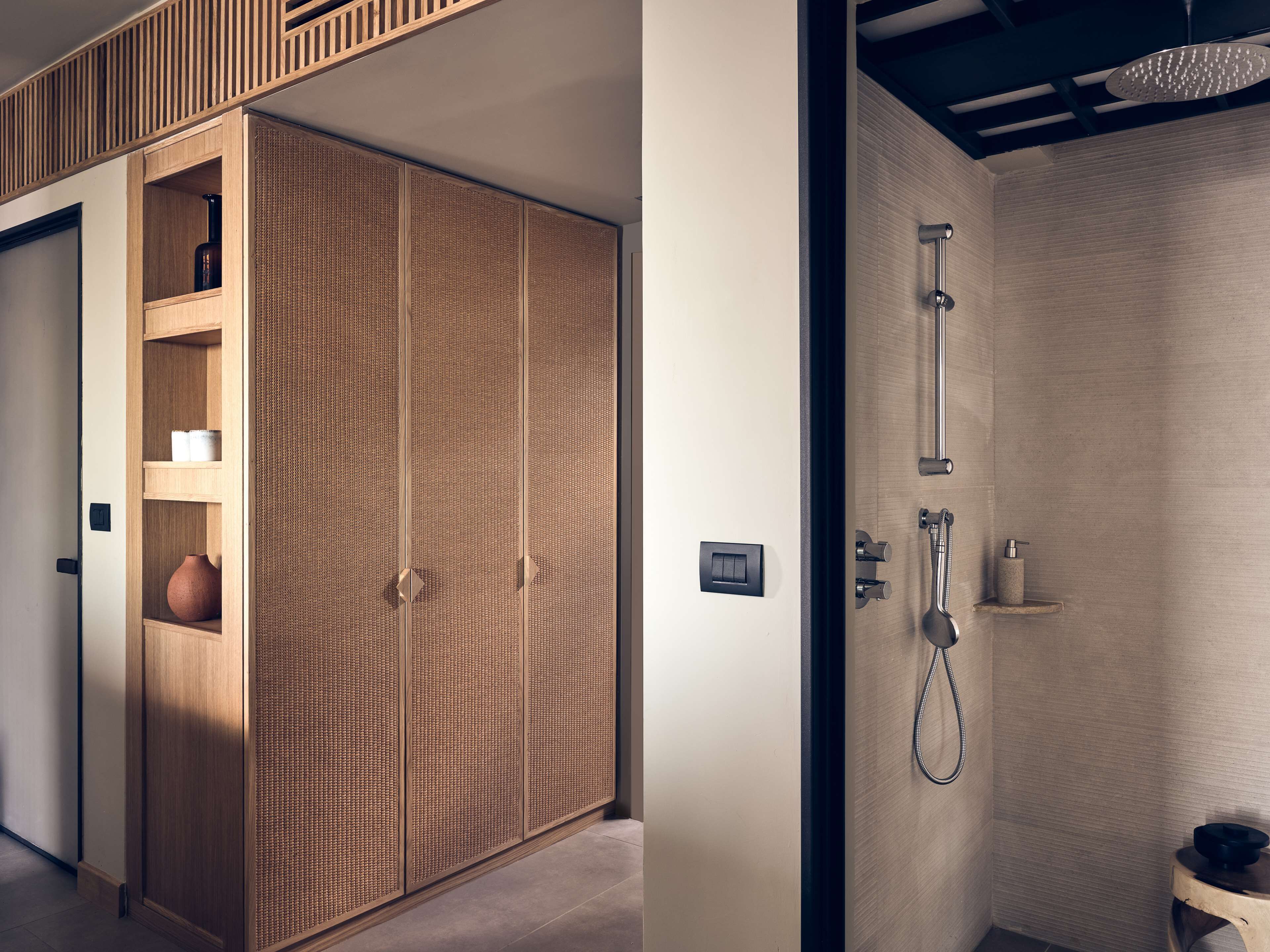 Et moderne badeværelse med bruser, et træskab og en hylde med toiletartikler.