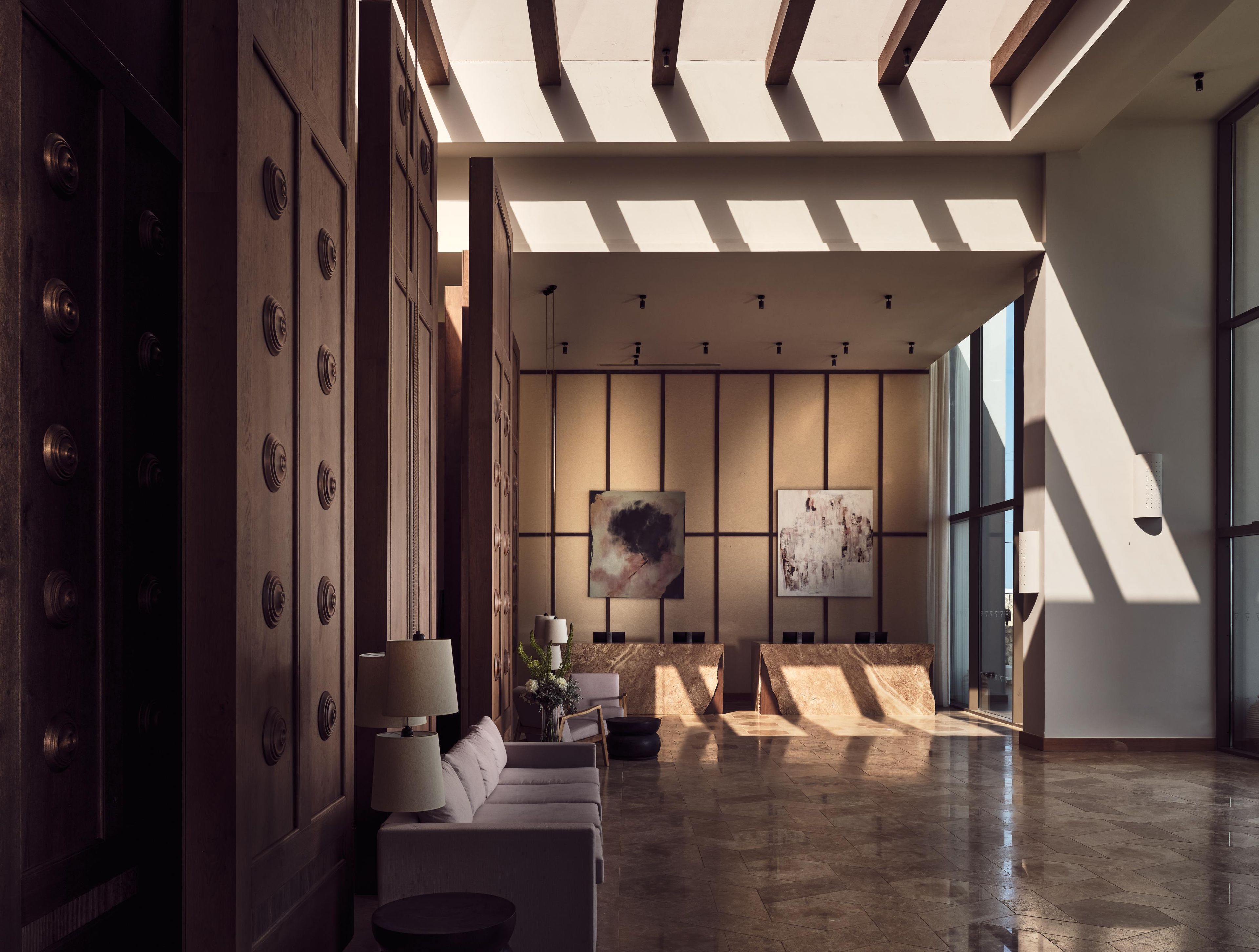 A spacious lobby with a modern design, featuring a sofa, lamps, and artwork on the walls.