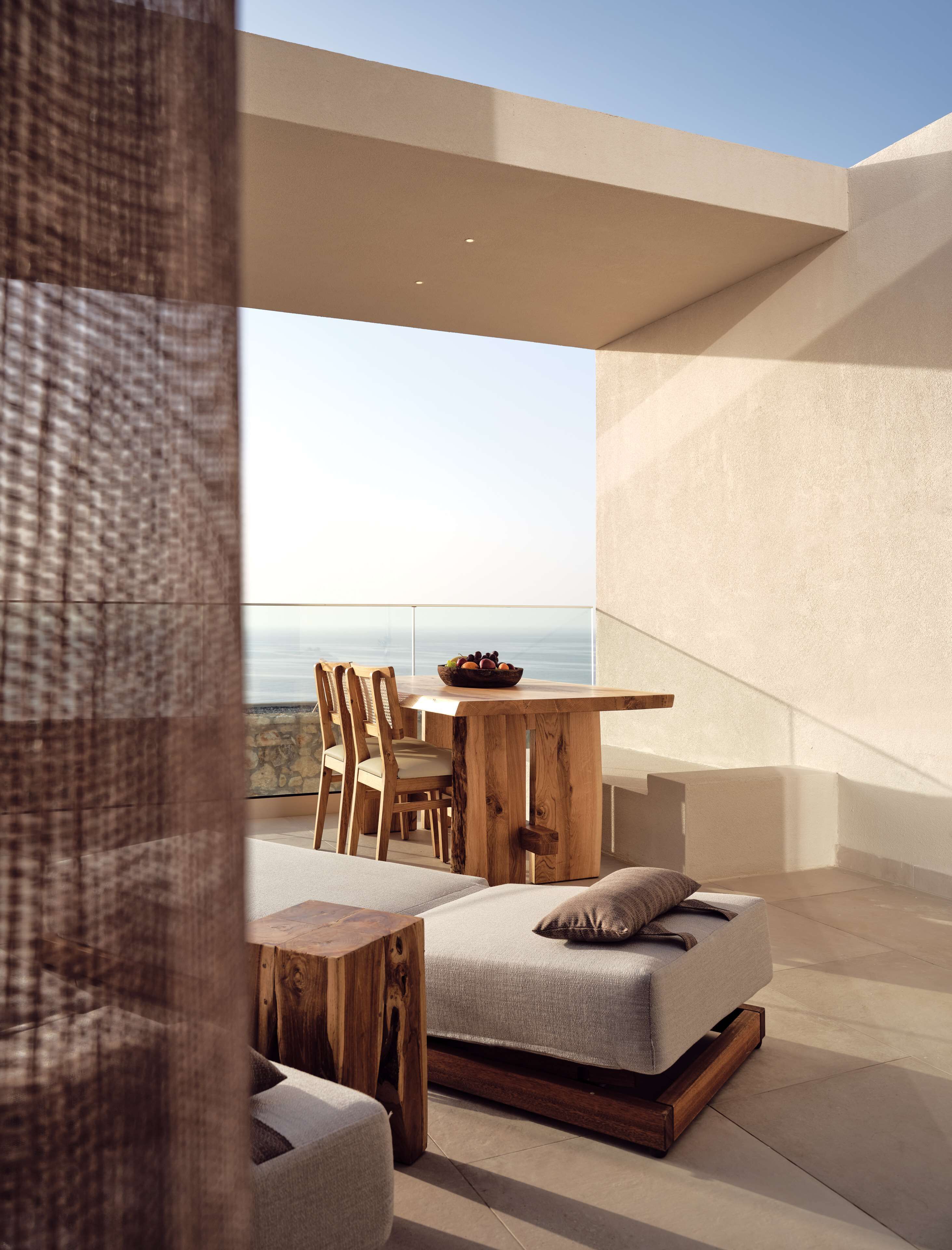 A modern outdoor living space with a wooden table, chairs, and a sofa.