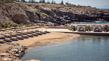A beach resort with sun loungers, umbrellas, and a pool area.