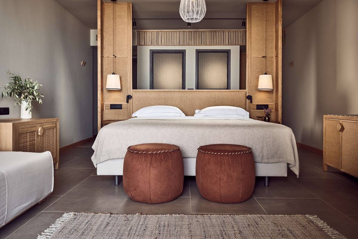 Un dormitorio moderno con una cama grande, dos mesitas de noche, una lámpara colgante y un cabecero tejido.