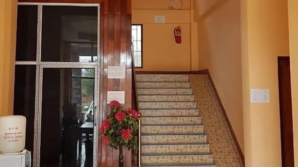 Un espace d’accueil comprenant un bureau en bois, une porte en verre, un escalier et un luminaire décoratif au plafond.