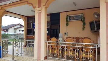 Un espacio al aire libre cubierto con barandilla de metal, un banco de madera y un televisor fijado a la pared.