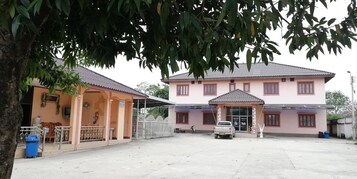 Un edificio de dos pisos con un porche cubierto y un vehículo estacionado adelante.