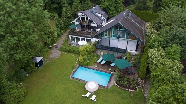 A large house with a swimming pool, surrounded by lush greenery. - Immas Welt (Utting am Ammersee)