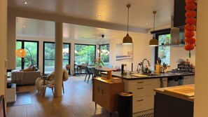 A modern kitchen with a central island, large windows, and a dining area with a view of the outdoors. - Immas Welt (Utting am Ammersee)