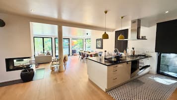 A modern kitchen with a central island, large windows, and a dining area with a view.