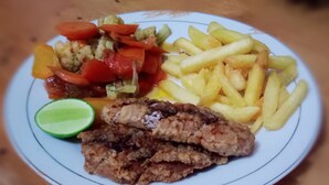 Un plato con pollo frito, papas fritas y una guarnición de verduras mixtas.