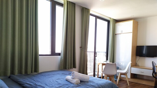 Quarto de hotel com uma cama, uma escrivaninha, uma cadeira e uma televisão.