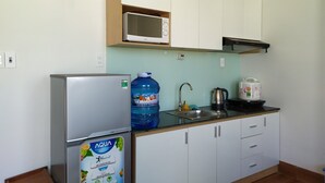 Uma cozinha compacta com geladeira, micro-ondas, bebedouro e chaleira.