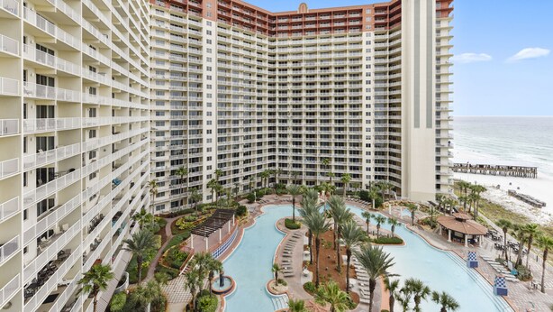 Un hotel de gran altura con varios balcones, piscina y vista a la playa.