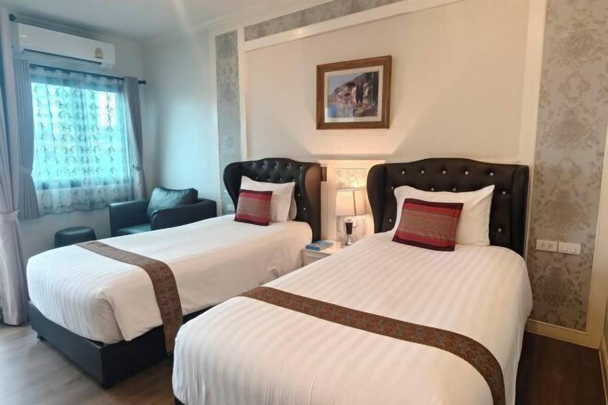 Habitació d'hotel amb dos llits, un sofà, una làmpada i un quadre a la paret.