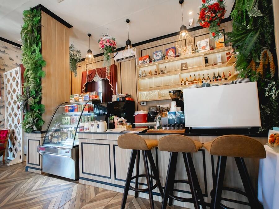 A bar area with stools, a counter, and shelves with bottles.