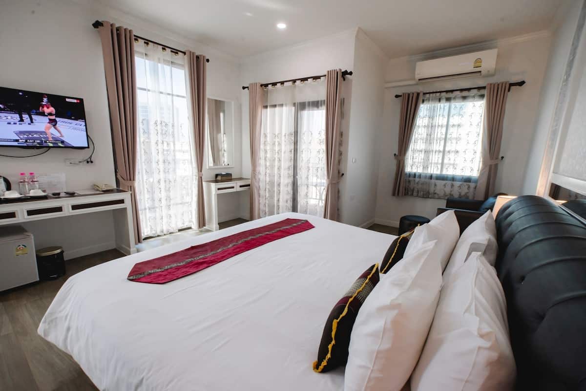 Een hotelkamer met een bed, een bureau, een televisie en een raam met gordijnen.