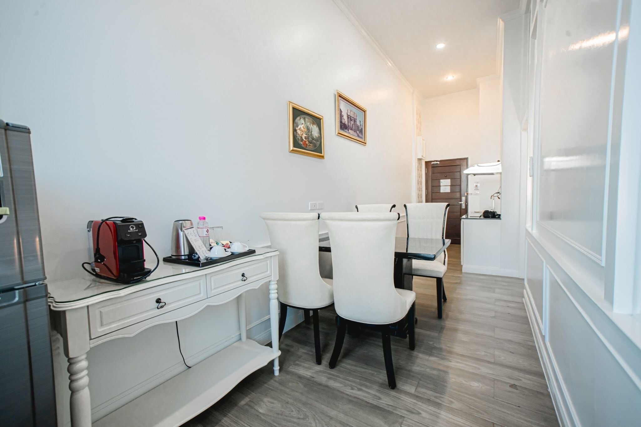 A compact kitchen with a white countertop, a coffee machine, and two chairs.
