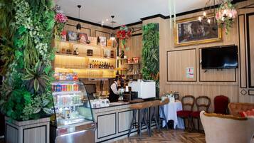 Zona de bar con un cantinero, estantes con botellas, una barra y taburetes.
