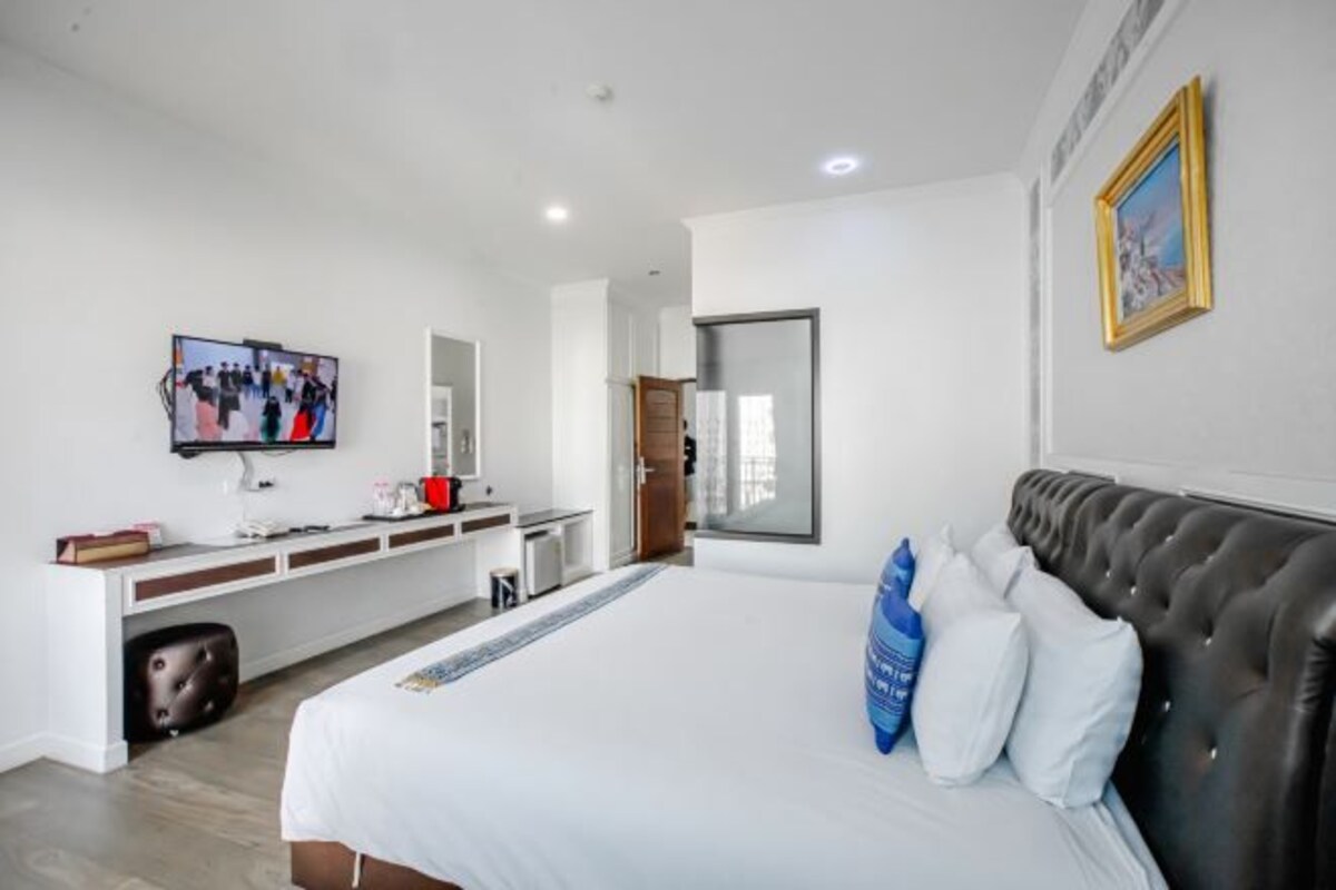 Een moderne hotelkamer met een groot bed, een flatscreen televisie, een bureau met een computer en een spiegel.
