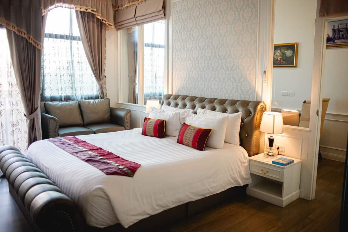 Een verzorgde hotelkamer met een groot bed, een nachtkastje met een lamp en een stoel.