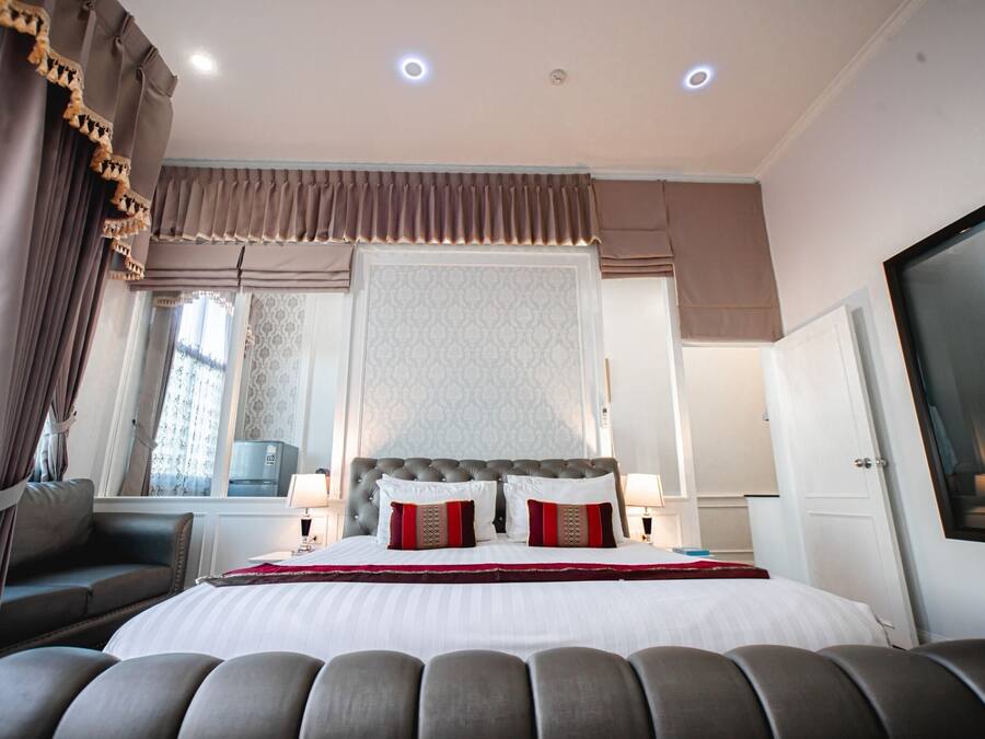 Habitación de hotel con una cama grande, un sofá, un televisor y una ventana con cortinas.