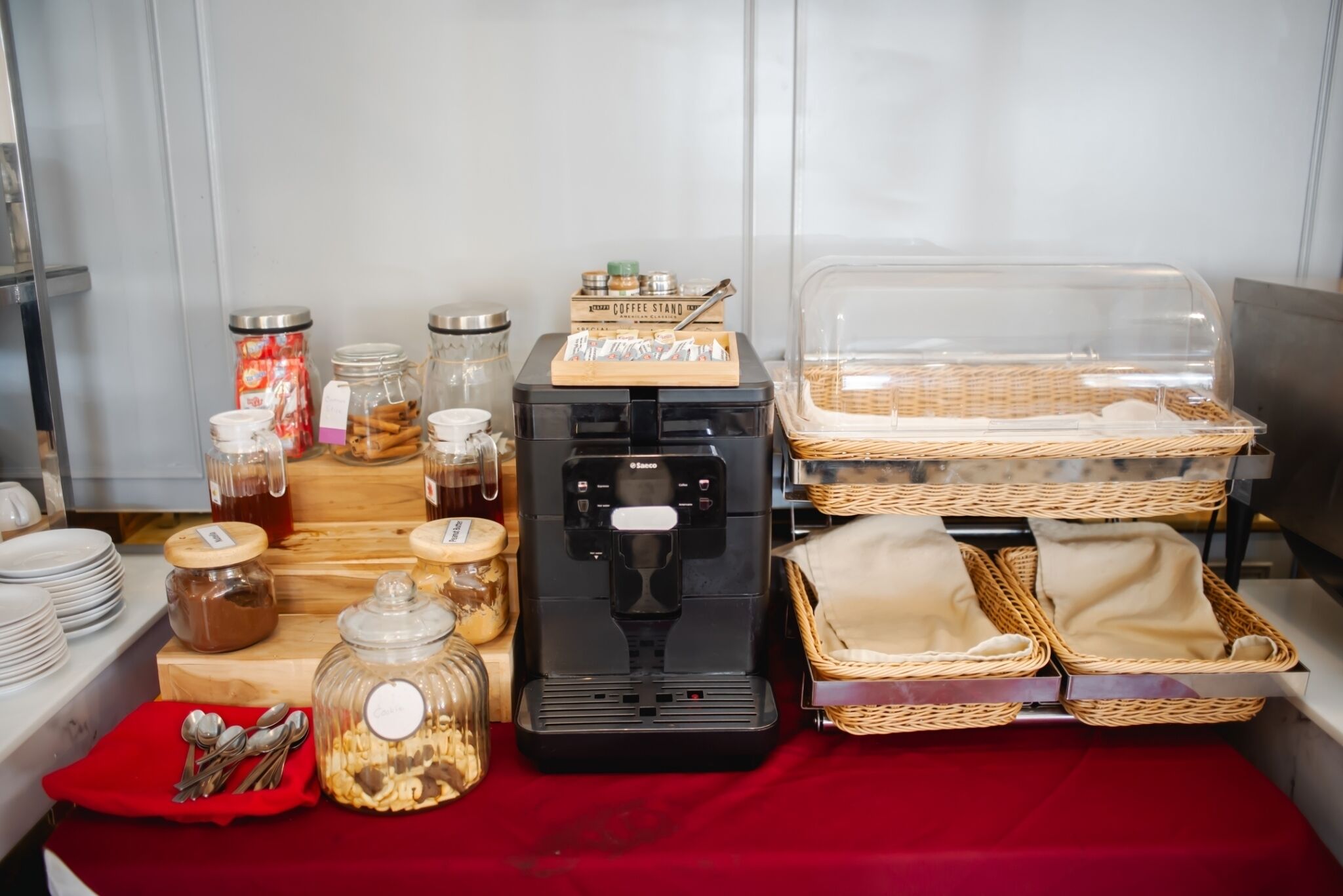 Montaje de bufé con diversos alimentos, una máquina de café y cestas.