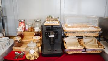 Montaje de bufé con diversos alimentos, una máquina de café y cestas.