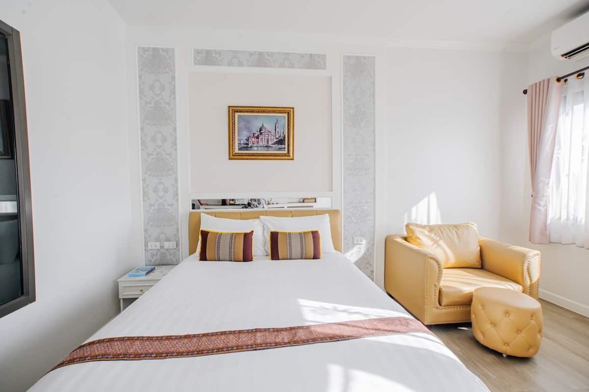 Een hotelkamer met een groot bed, een bank, een kleine tafel en een schilderij aan de muur.
