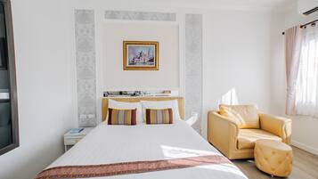 Een hotelkamer met een groot bed, een bank, een kleine tafel en een schilderij aan de muur.