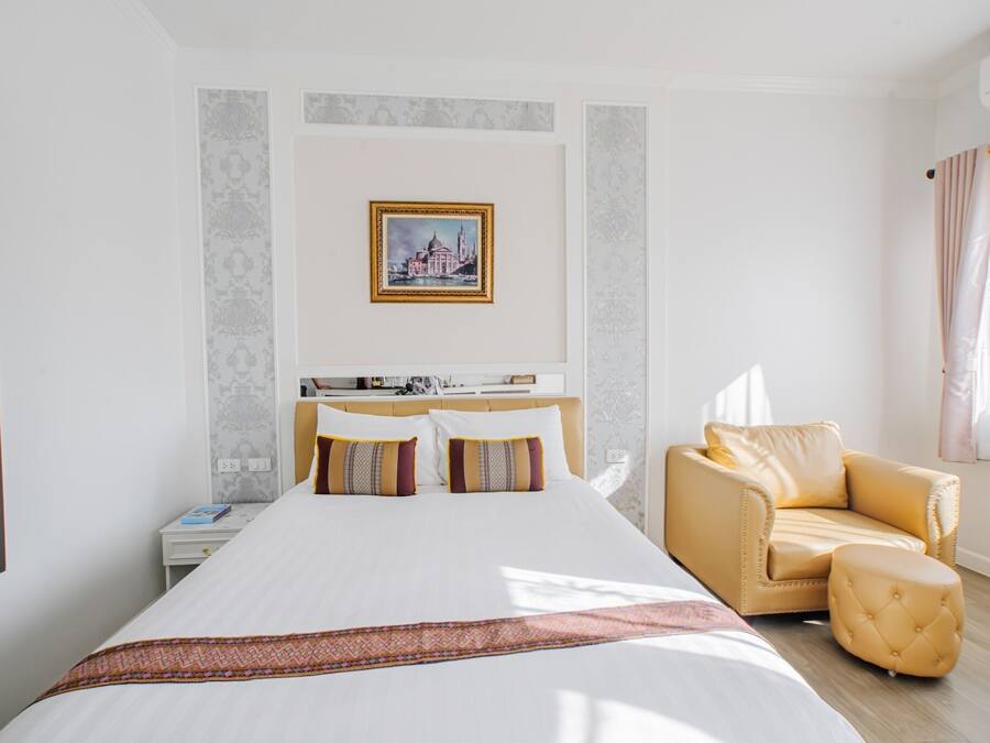 Una habitación de hotel con una cama grande, un sofá, una mesita y un cuadro en la pared.