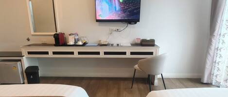 A hotel room with two beds, a TV mounted on the wall, a desk with a chair, and a mirror.