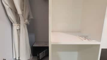 Um closet espaçoso com barra para pendurar roupas e prateleiras, um rádio pequeno e uma revista na prateleira de cima.