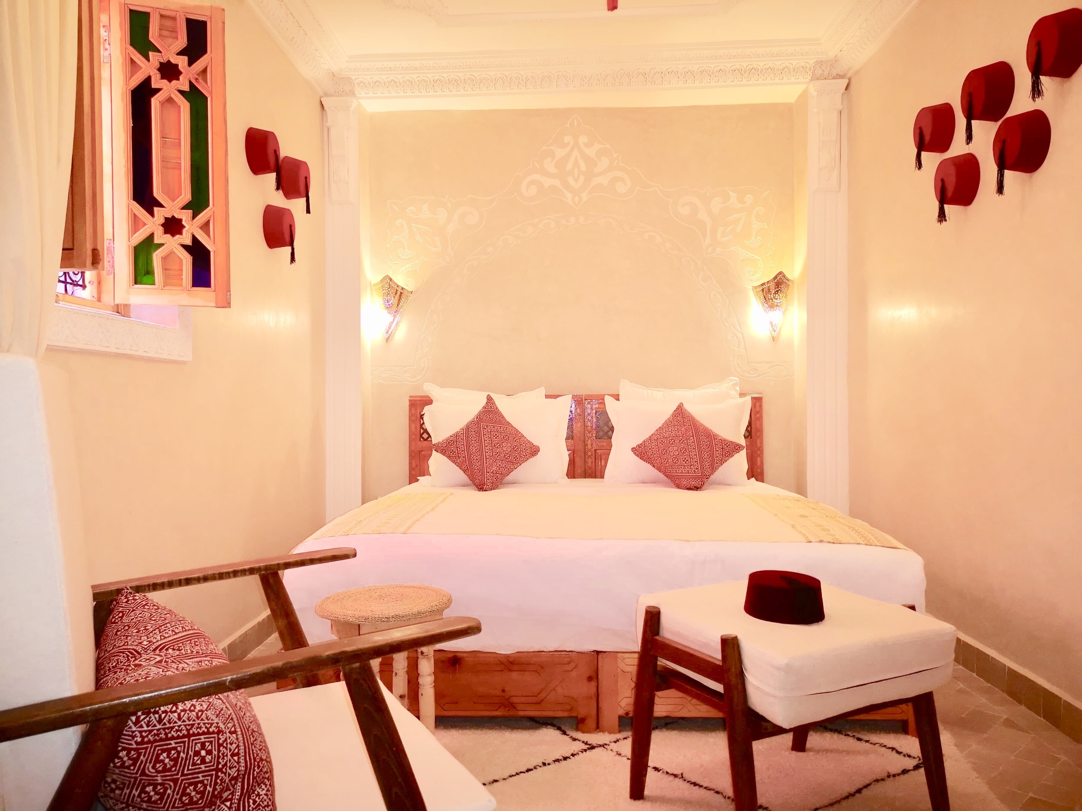 Une chambre bien rangée, avec un lit, des tables de chevet et une chaise.