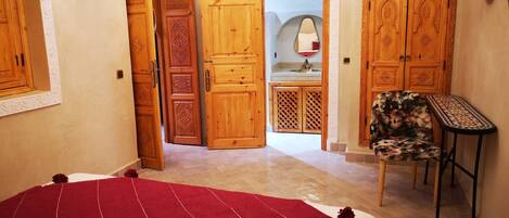 A bedroom with a bed, a chair, and wooden wardrobes.