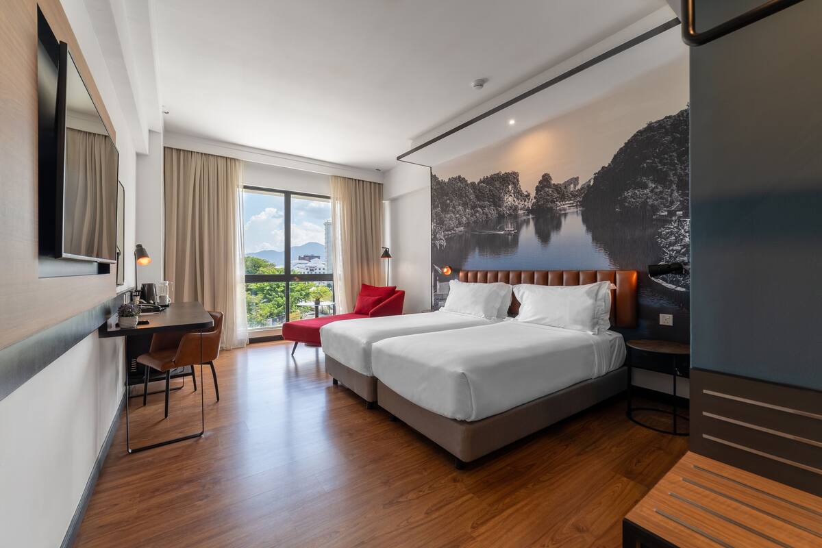 A modern hotel room with a large bed, a desk, a chair, and a balcony with a scenic view.
