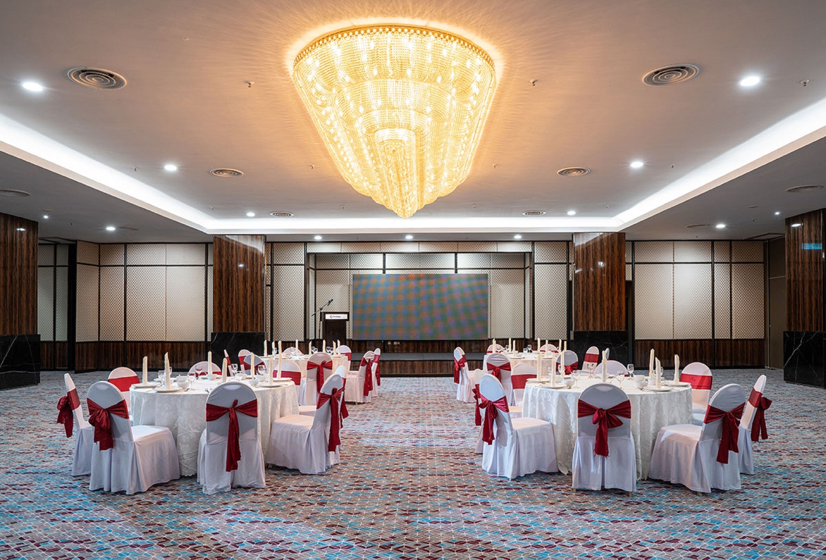 A banquet hall with round tables, white tablecloths, and red sashes.