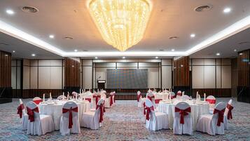 A banquet hall with round tables, white tablecloths, and red sashes.