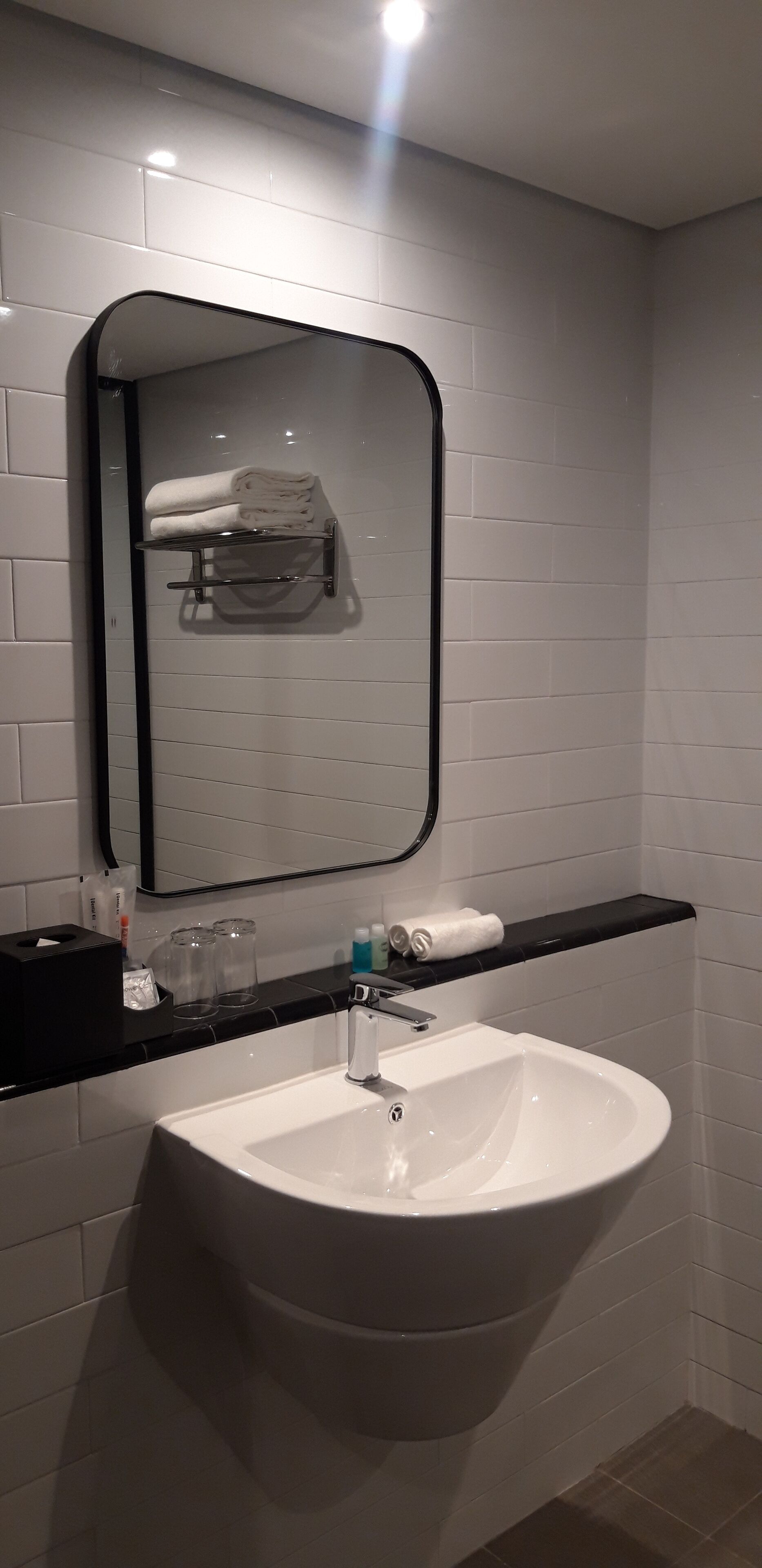 A bathroom with a white sink, a mirror, and a towel rack.