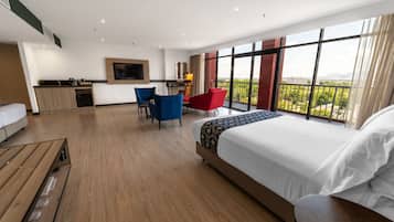 A modern hotel room with a large bed, a desk, a chair, and a balcony with a view.