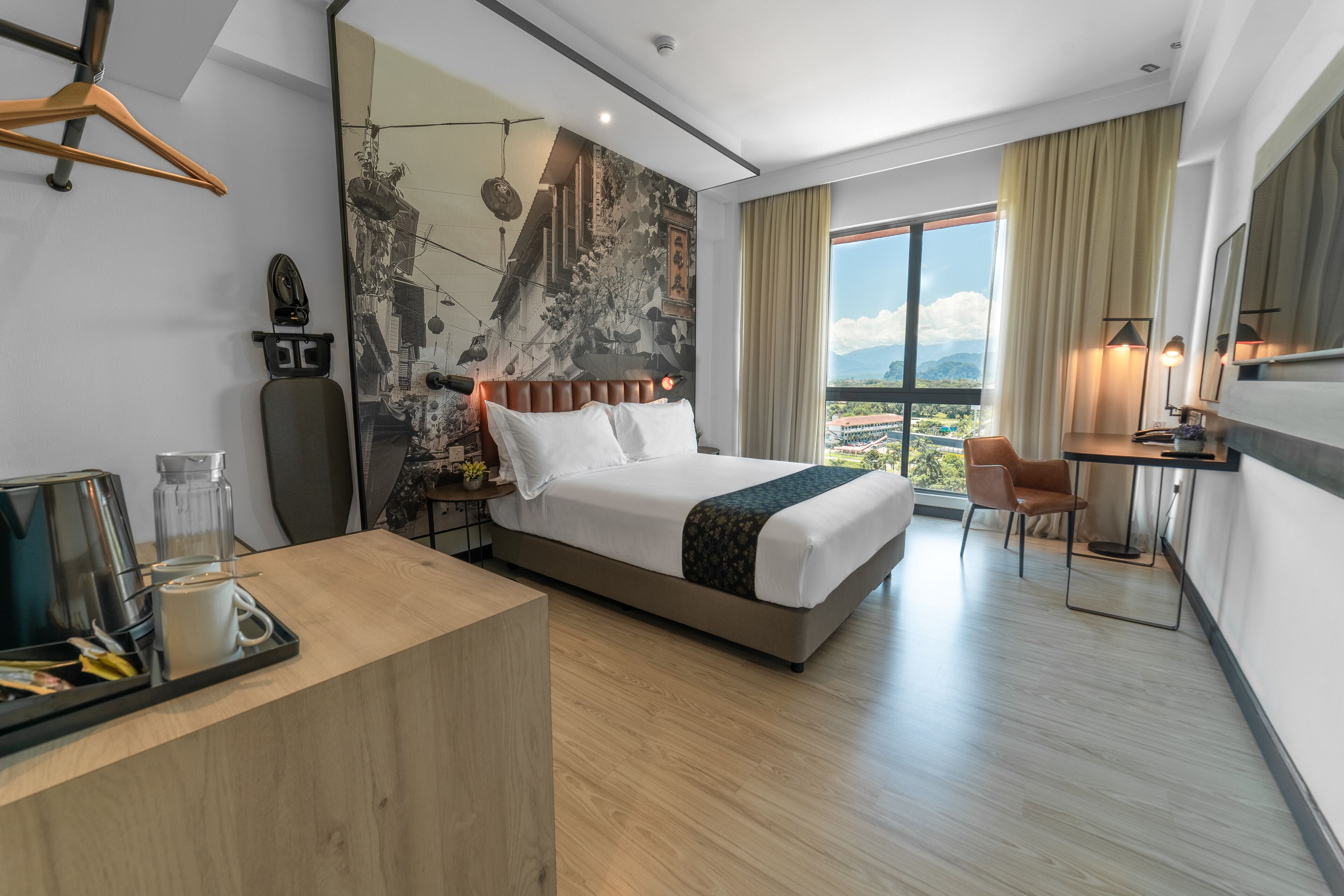 A modern hotel room with a large bed, a desk, and a view of the city.