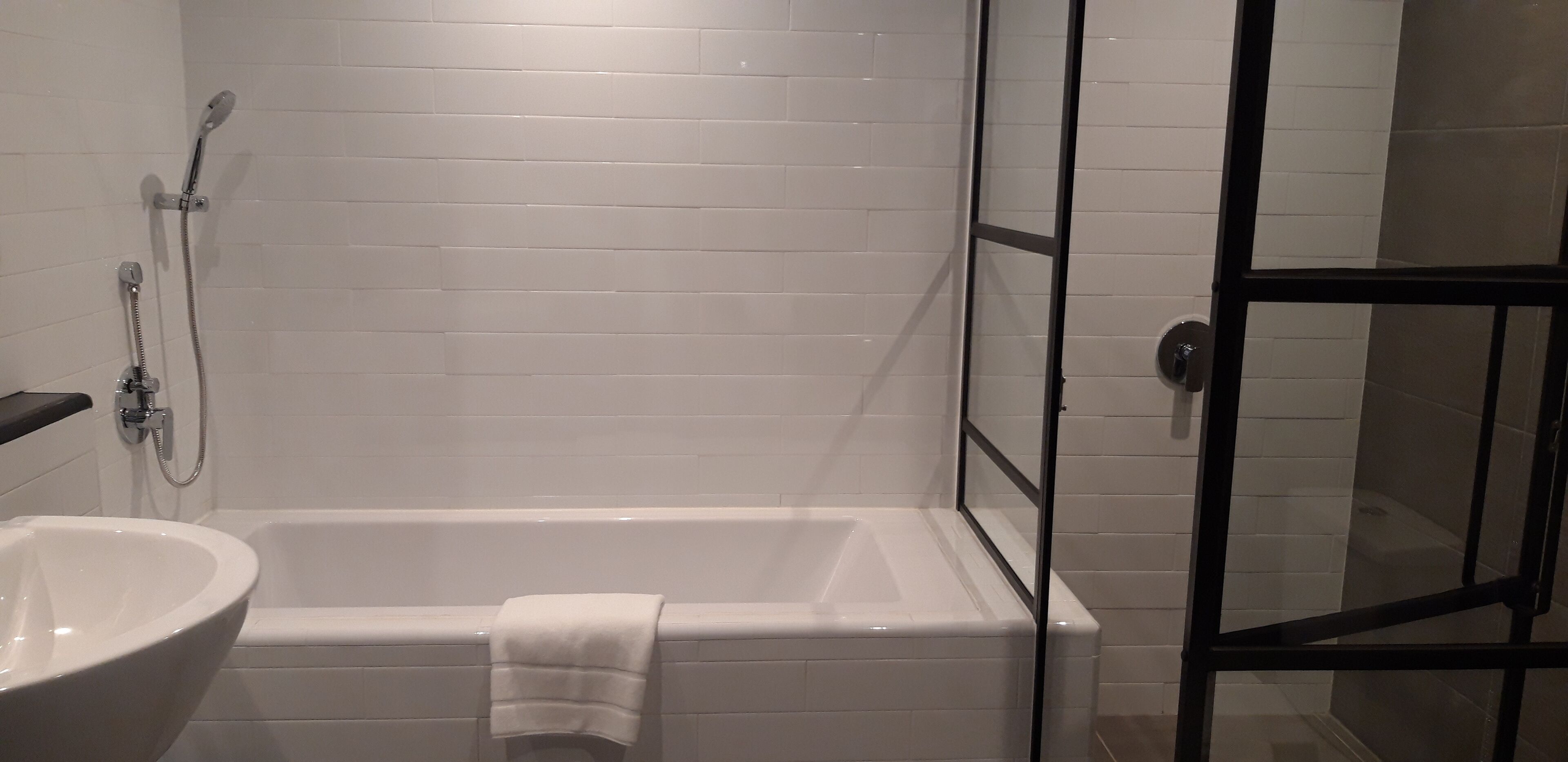 Un baño con una bañera blanca, un lavamanos blanco y una cabina de ducha con mampara de vidrio.
